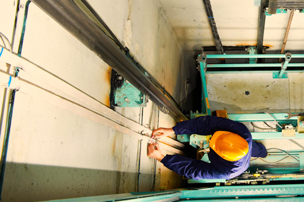 Machinists Adjusting Lift In Elevator Hoistway