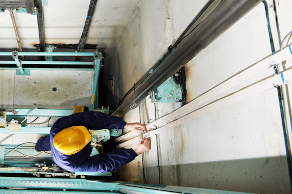 Machinists Adjusting Lift In Elevator Hoistway