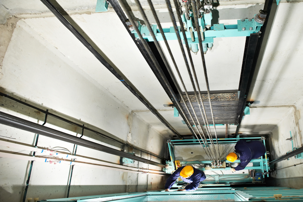 Machinists Adjusting Lift In Elevator Hoistway